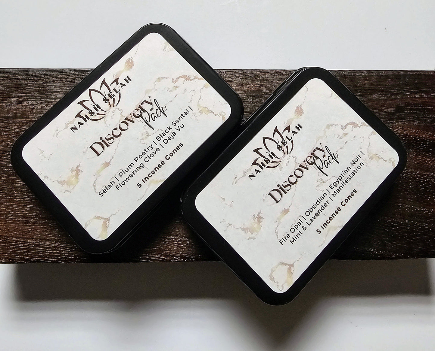 Two black tins labeled 'Discovery Pack' on a wooden surface.
