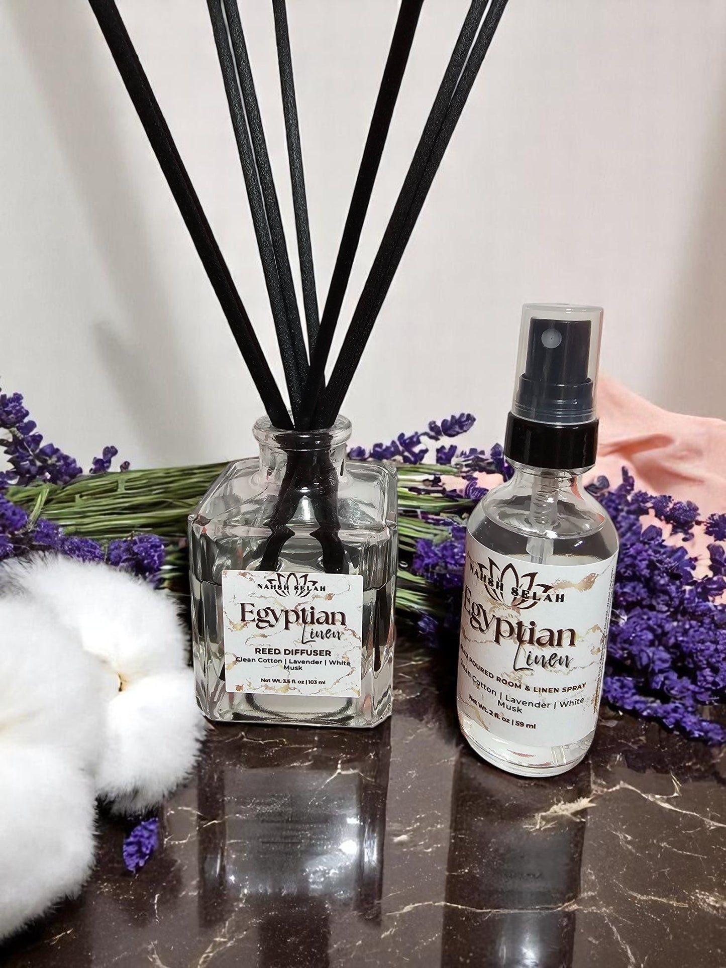 Diffuser set with black reeds and lavender flowers on a reflective surface