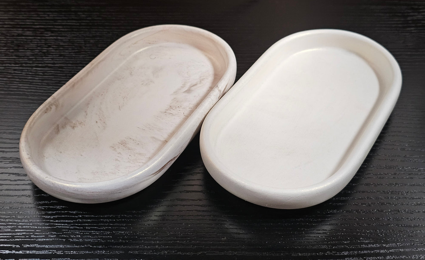 Two white ceramic dishes on a black wooden surface