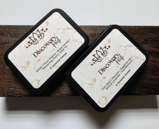 Two black tins labeled 'Discovery Pack' on a wooden surface.