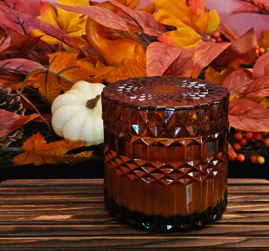 Decorative brown candle with autumn leaves and pumpkins in the background