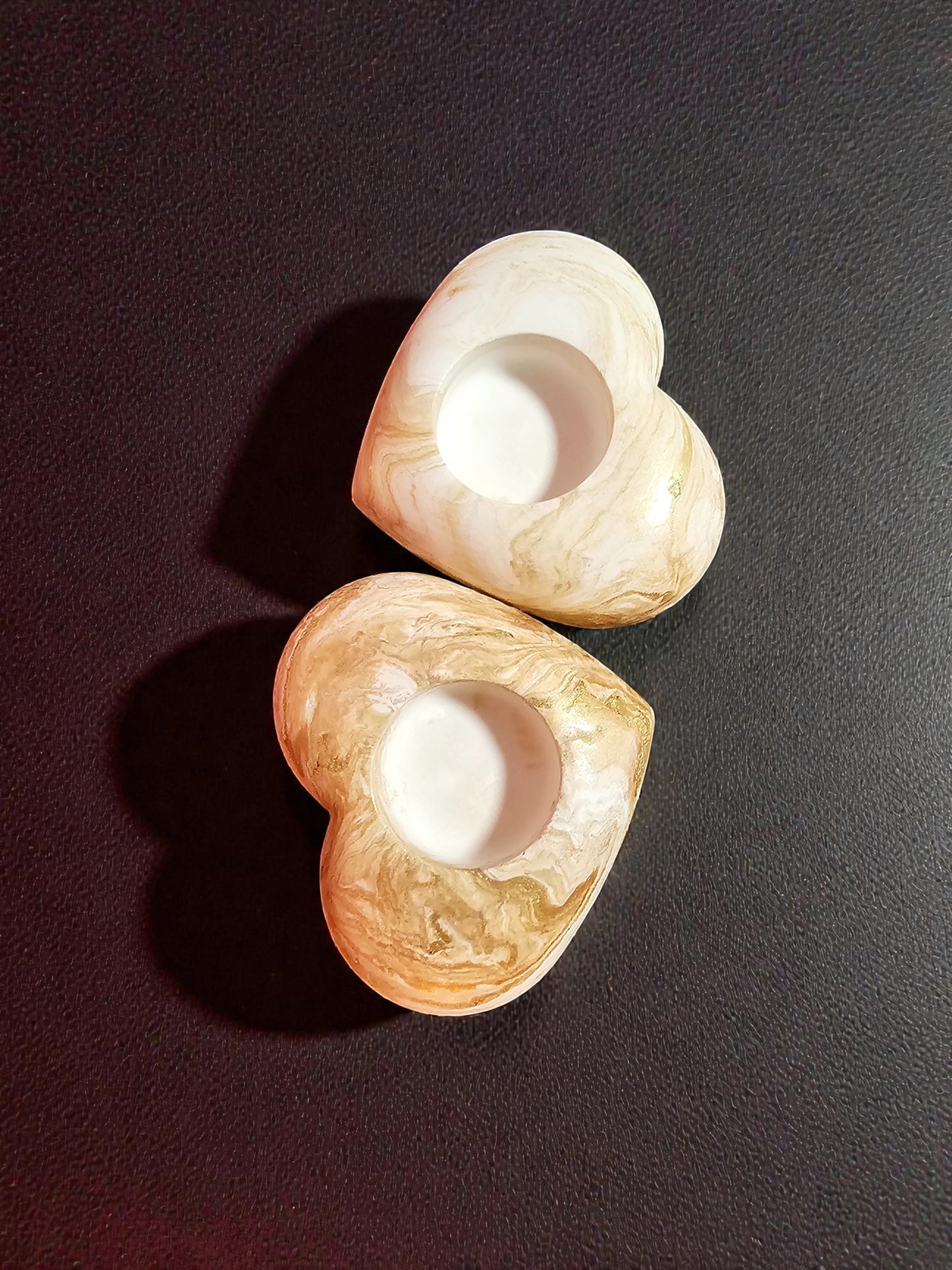 Two heart-shaped tea light holder on a dark surface