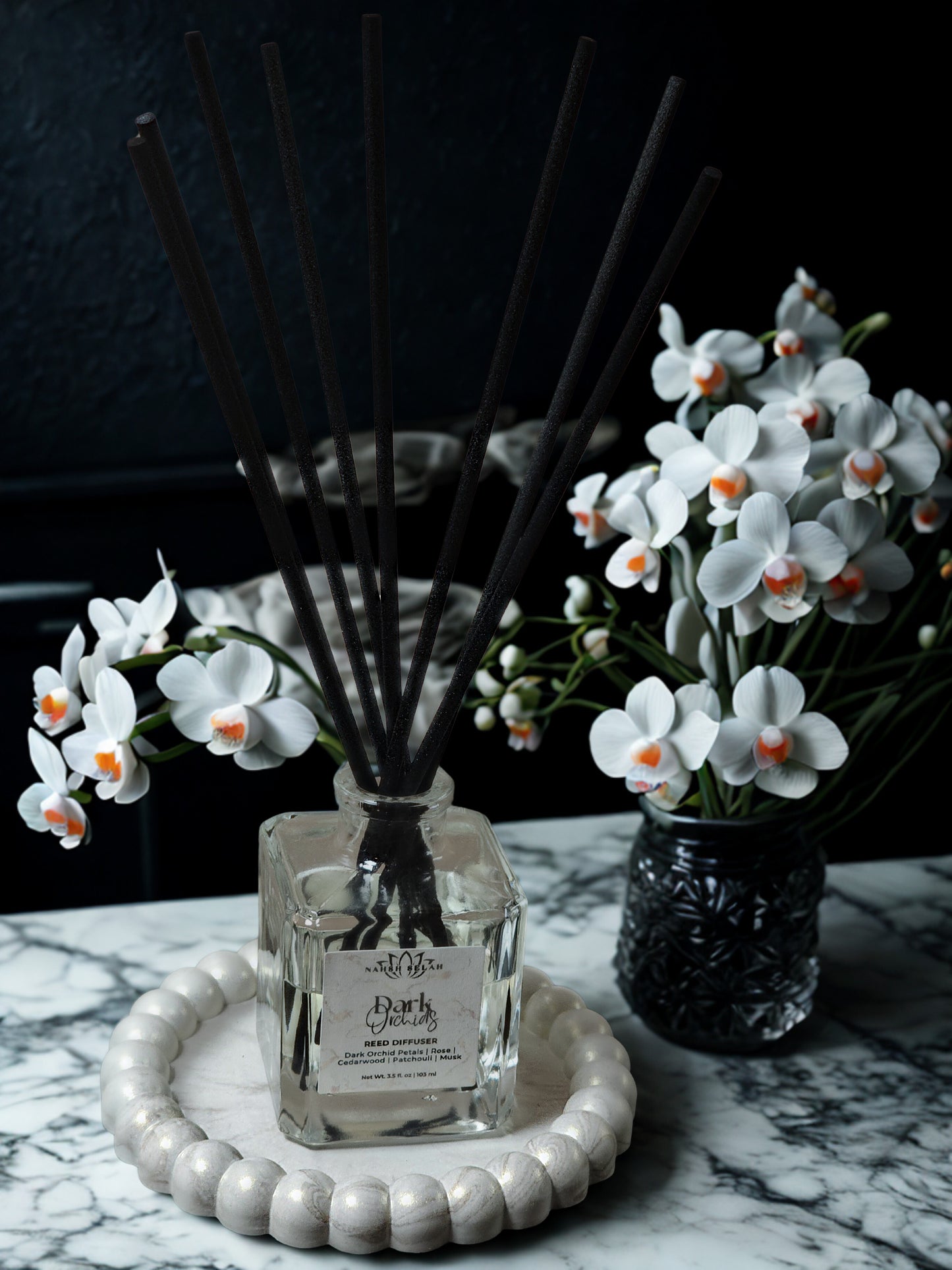 Reed diffuser with decorative flowers on a marble surface