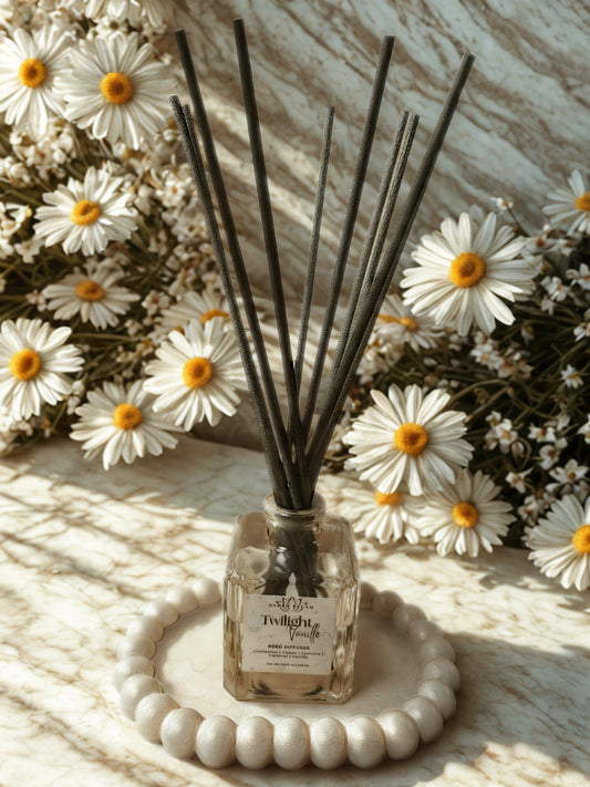 Diffuser with reeds surrounded by white flowers on a textured surface