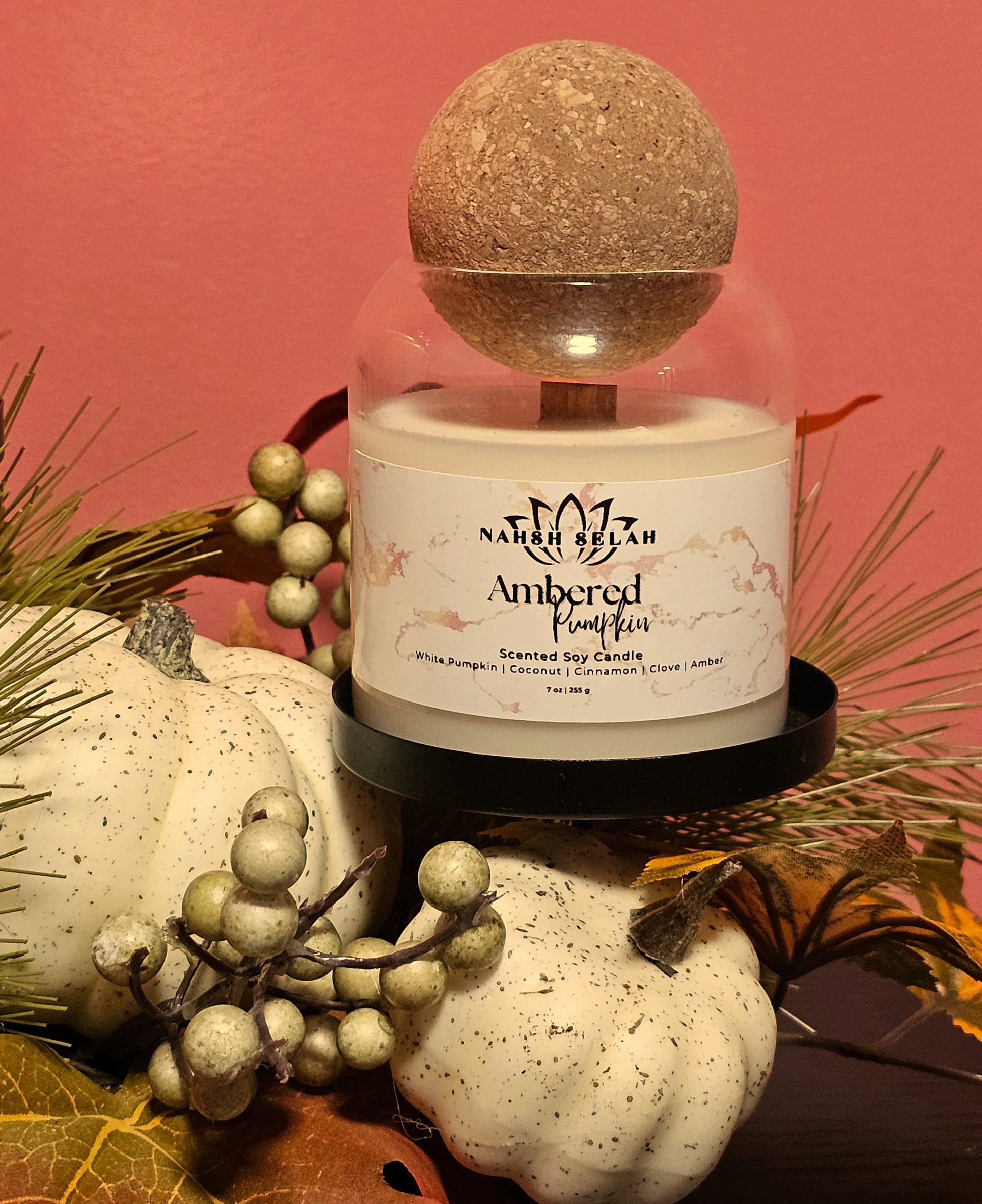Scented candle in a decorative glass cover with pumpkins and berries on a pink background