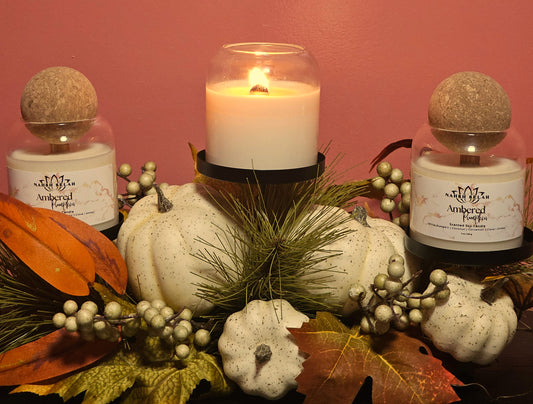 Decorative setup with candles, pumpkins, and autumn leaves against a pink background