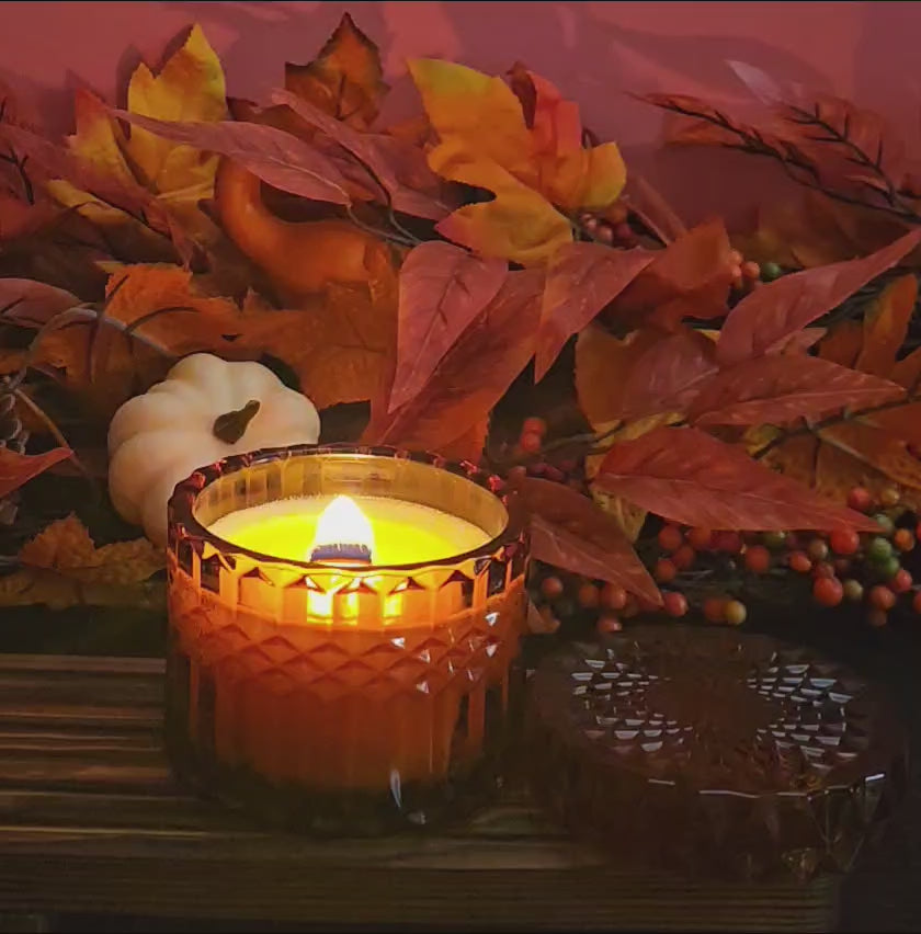 Video of Decorative brown candle burning with autumn leaves and pumpkins in the background